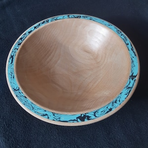May include: A wooden bowl with a light wood finish and a blue and black marbled rim.