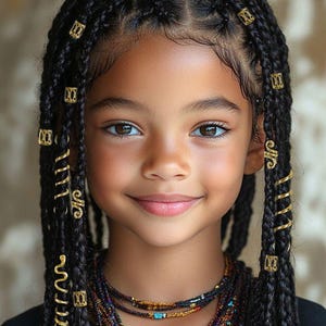May include: A portrait of a young person with dark skin and brown eyes, smiling. Their hair is styled in long, black braids, adorned with gold-colored decorative beads and spirals. A multi-strand beaded necklace is worn around the neck.