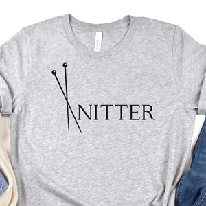 May include: Gray t-shirt with a black graphic of knitting needles and the word "Knitter".
