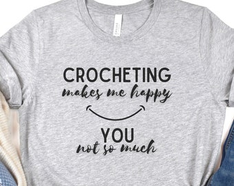 May include: Gray t-shirt with the text "Crocheting makes me happy" and a smiley face. Below the smiley face is the text "You not so much".