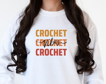 May include: White sweatshirt with the text "CROCHET VIBES CROCHET" in orange, red, and brown.