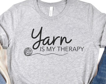 May include: Gray t-shirt with the text "Yarn is my therapy" and a stylized image of a ball of yarn.