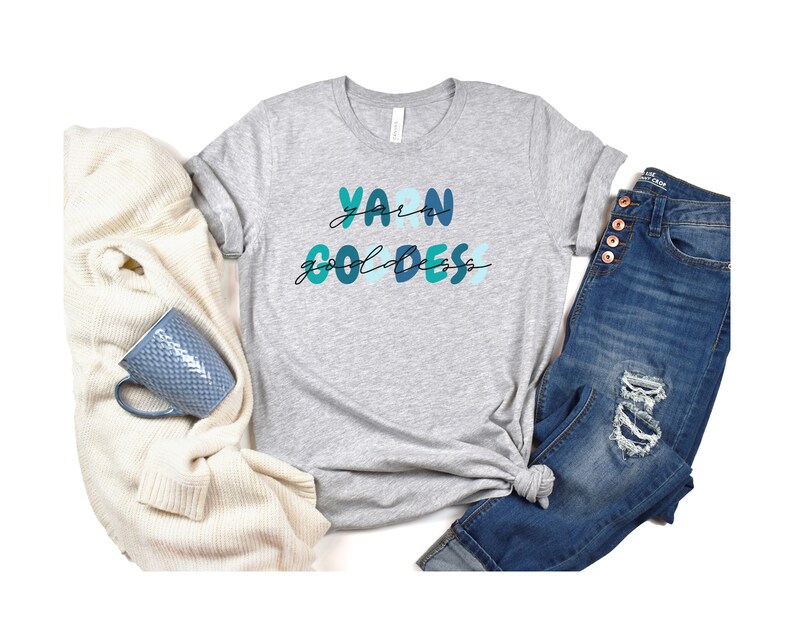 May include: Gray t-shirt with the text "Yarn Goddess" in blue and green lettering.