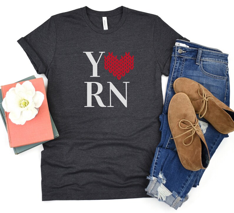 May include: A dark gray t-shirt with the text "Y RN" in white and a red knitted heart in the center.