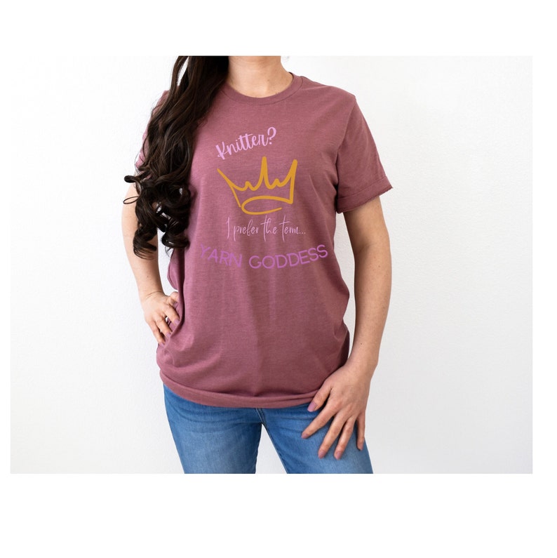 May include: A mauve t-shirt with a gold crown and the text "Knitten? I prefer the yarn... YARN GODDESS" in pink.