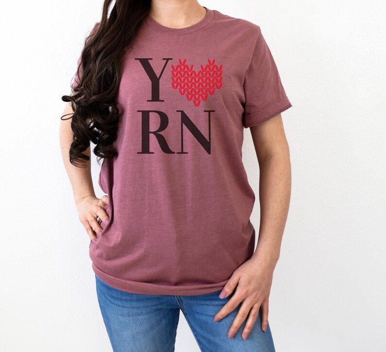 May include: A mauve t-shirt with the text "Y" followed by a red knitted heart and the text "RN".