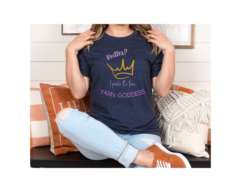 May include: A navy blue t-shirt with a gold crown and the text "Knitter? I prefer the term YARN GODDESS" in pink.