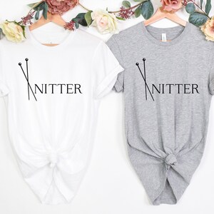May include: Two t-shirts with the text "Knitter" and a graphic of knitting needles. One shirt is white and the other is gray.