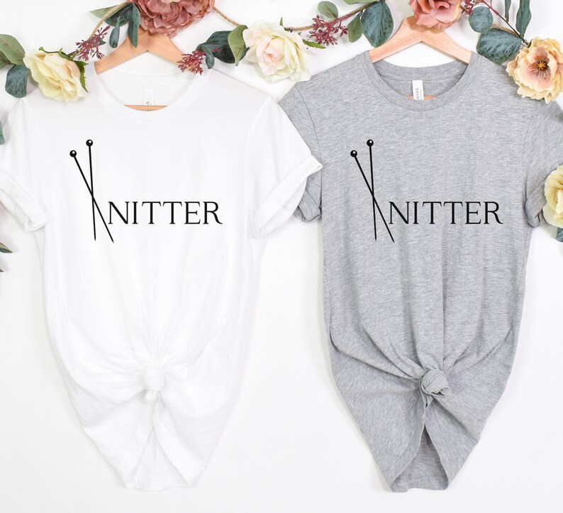 May include: Two t-shirts with the text "Knitter" and a graphic of knitting needles. One shirt is white and the other is gray.