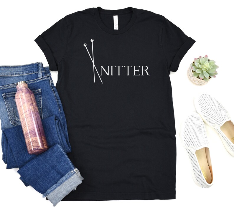 May include: Black t-shirt with white text that says "Knitter" and a graphic of two knitting needles.