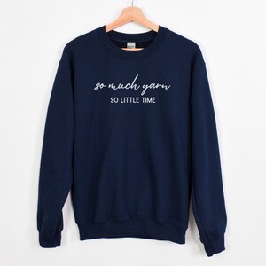 May include: Navy blue sweatshirt with the text "so much yarn so little time" in white.
