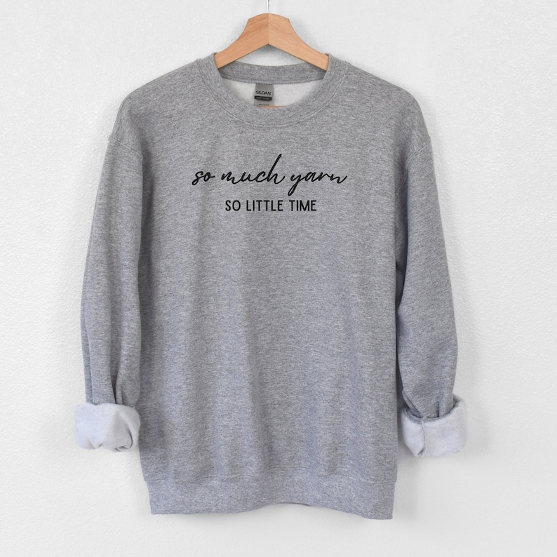 May include: Gray sweatshirt with the text "so much yarn so little time" in black.