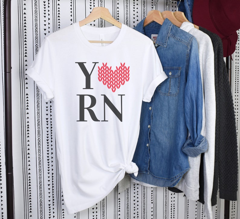 May include: White t-shirt with a red knitted heart and the text "Y RN" printed on the front.
