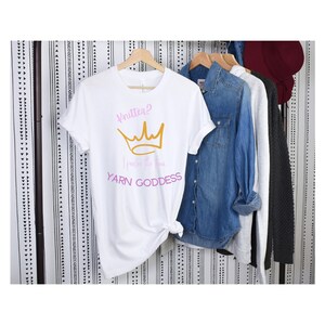 May include: White t-shirt with a pink and gold crown graphic and the text "Knitten? I prefer the term YARN GODDESS".