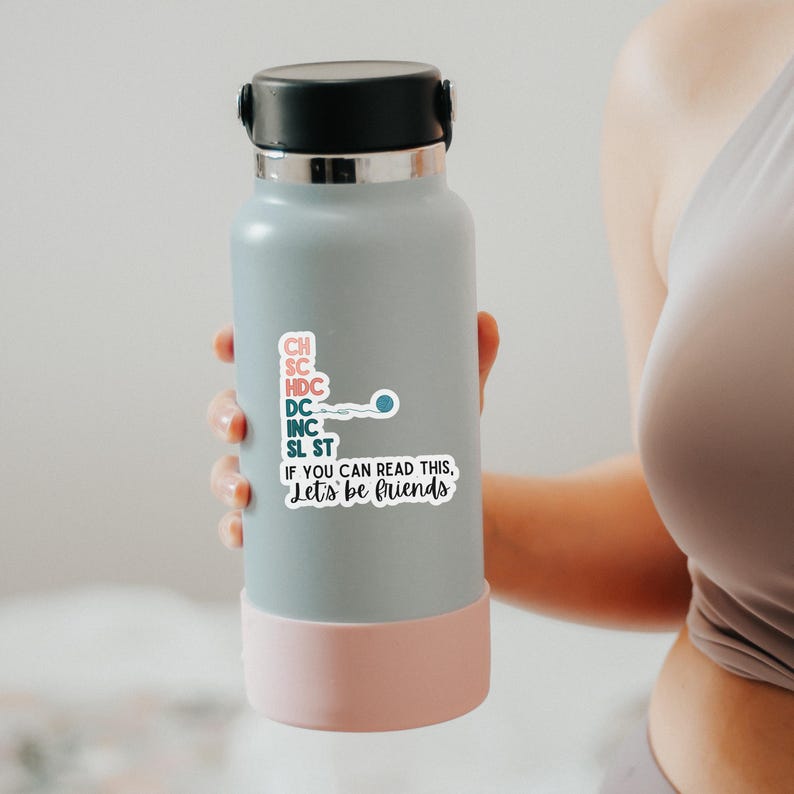 May include: A light blue water bottle with a black cap and a pink base. The bottle has a sticker with the text "IF YOU CAN READ THIS, Let's be friends" and other abbreviations. A blue and white sperm cell graphic is also on the sticker.