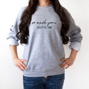May include: A gray sweatshirt with the text "so much yarn so little time" printed on the front.