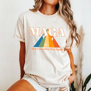 May include: A white t-shirt with a rainbow graphic and the text "MAGA Make America Gay Again".