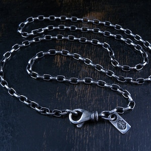 May include: A silver chain necklace with a silver clasp. The chain is made of small, oval links.
