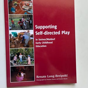 May include: A red book titled Supporting Self-directed Play in Steiner/Waldorf Early Childhood Education by Renate Long-Breipohl, with photographs by Paulene Hanna and Sandra Busch. The cover features five small photographs of children playing.