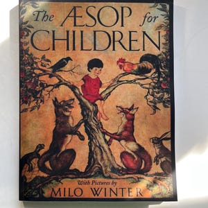 May include: A hardcover book titled "The ÆSOP for CHILDREN" with illustrations by Milo Winter. The cover features a child, foxes, a crow, a rooster, and a rabbit in a tree, set against a sepia-toned background.