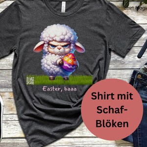 Könnte beinhalten: Ein dunkelgraues T-Shirt mit einem Cartoon-Bild eines weißen Schafes, das ein buntes Osterei hält. Der Text "Easter, baaa" ist unter dem Bild gedruckt. Der Text "Shirt mit Schaf-Blöken" ist auf einem roten Kreis in der unteren rechten Ecke des Bildes gedruckt.