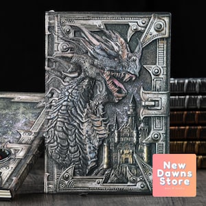 Peut inclure: Un journal argenté et noir avec un motif en relief de dragon et de château. Le journal a une fermeture à fermoir métallique et une couverture texturée.