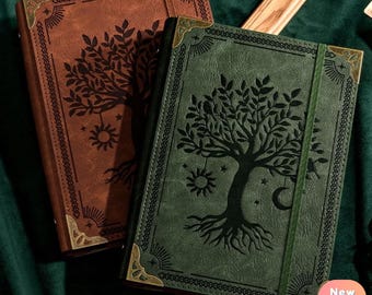 May include: Two leather-bound journals with a tree of life design. The journal on the left is brown and the journal on the right is green.
