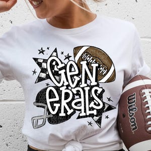 May include: White t-shirt with the text "Generals" in a stylized font, along with football graphics and stars. A brown and white football is held in the hand. The shirt has short sleeves.