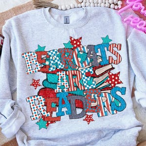 May include: Light gray sweatshirt with the text "BEARCATS ARE READERS" in red, white, and blue letters. The design includes stars and stacks of books, creating a patriotic and educational theme.