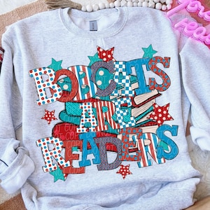 May include: A light gray sweatshirt with the words "BOBCATS ARE READERS" in red, white, and blue lettering. The design includes stacks of books and star accents. The sweatshirt is a crew neck style.