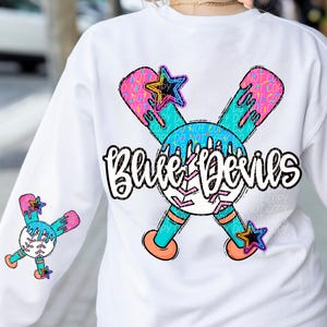 May include: White long-sleeve sweatshirt with a baseball-themed graphic. The design features crossed baseball bats, a baseball, and the text "Blue Devils" in a stylized font. The graphic includes blue, pink, and orange accents.