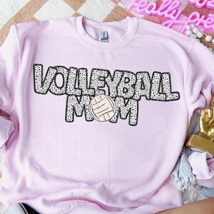 May include: Pink sweatshirt with a black and white graphic that says "Volleyball Mom" with a volleyball in the middle of the word "Mom".