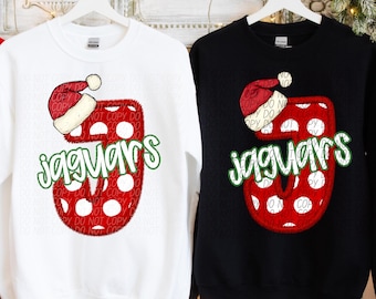 May include: Two sweatshirts, one white and one black, each featuring a red number 5 with white polka dots and a Santa hat. The word "jaguars" is written in green script below the number. The sweatshirts are hanging on white hangers.