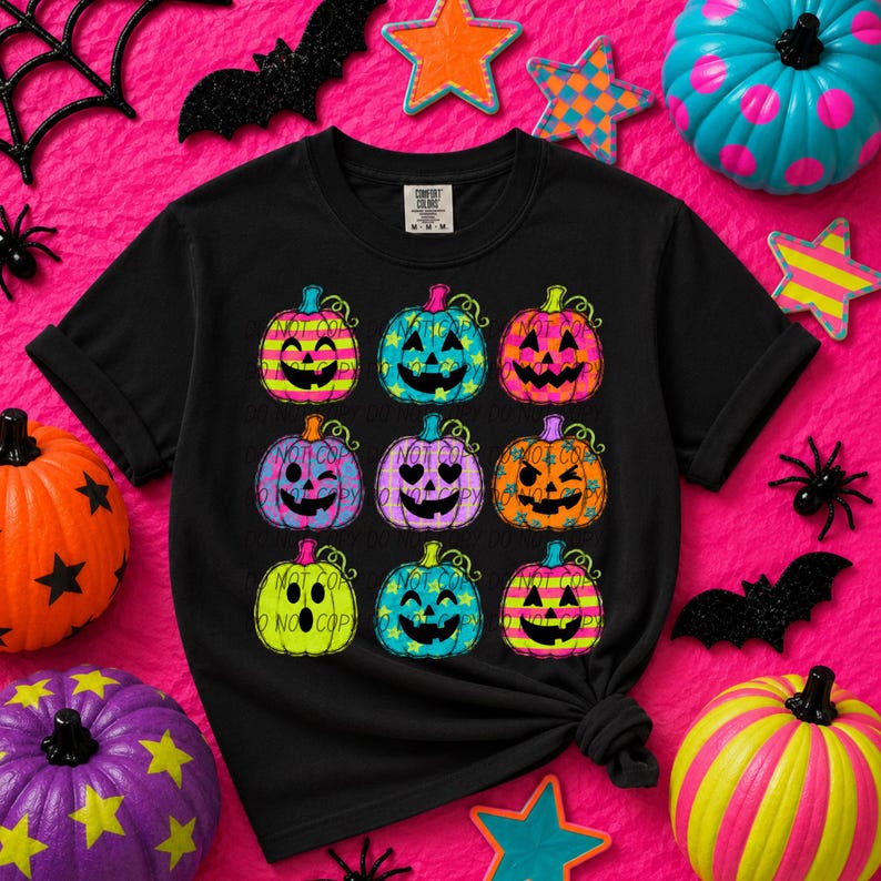 May include: A black short-sleeve t-shirt featuring a graphic print of nine colorful jack-o'-lanterns arranged in a grid. Each pumpkin displays a unique facial expression and pattern, including stripes, stars, and polka dots in neon colors.