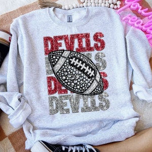 May include: Grey sweatshirt with a red and silver glitter design that says "Devils" with a football in the middle.