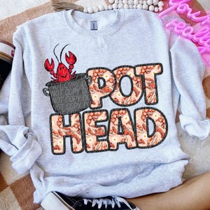 May include: A gray sweatshirt with a design of a pot of crawfish with the text "POT HEAD" in a crawfish pattern.