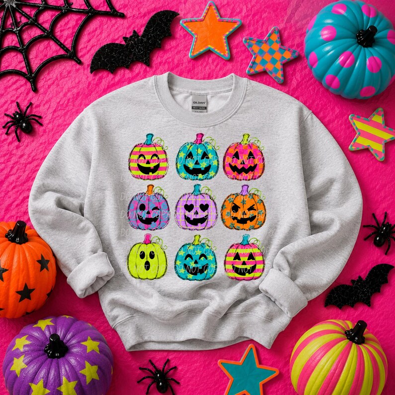May include: A light gray crewneck sweatshirt featuring a graphic print of nine colorful jack-o'-lanterns in three rows. The pumpkins display various patterns including stripes, stars, and polka dots in vibrant neon colors like pink, blue, and yellow.