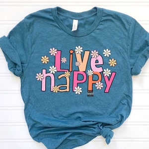 May include: A teal blue t-shirt with the words "Live Happy" in pink, orange, and white letters with white daisy flowers around the letters.