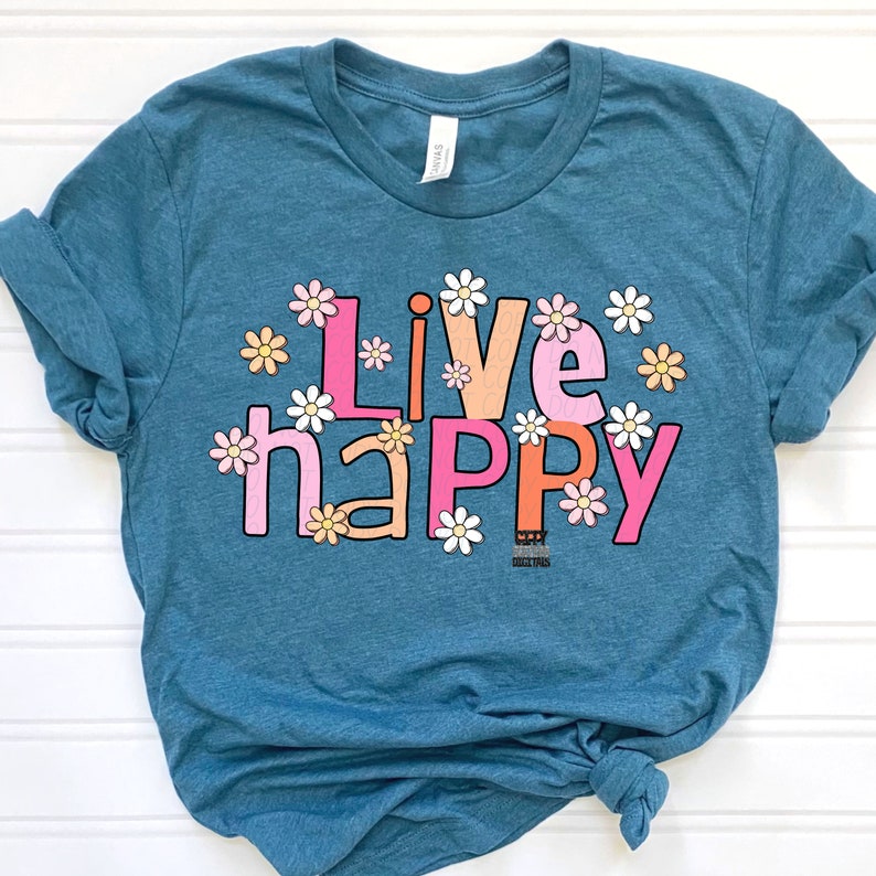 May include: A teal blue t-shirt with the words "Live Happy" in pink, orange, and white letters with white daisy flowers around the letters.