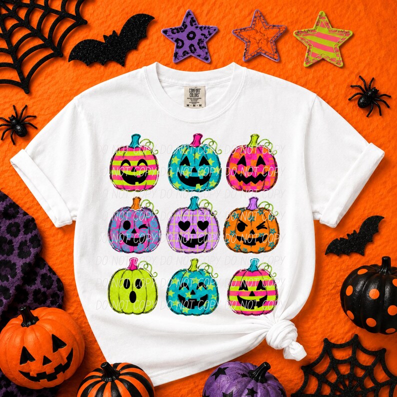 May include: A white short-sleeve t-shirt featuring a graphic print of nine colorful jack-o'-lanterns arranged in a grid. Each pumpkin displays a unique facial expression and pattern, including stripes, stars, and plaid in neon pink, blue, and orange.