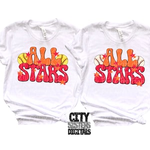 Pu&ograve; includere: Due magliette bianche con il testo "All Stars" in un font retr&ograve;, con colori arancioni e rossi. Il testo &egrave; decorato con piccole foglie arancioni e rosse e palline da baseball.