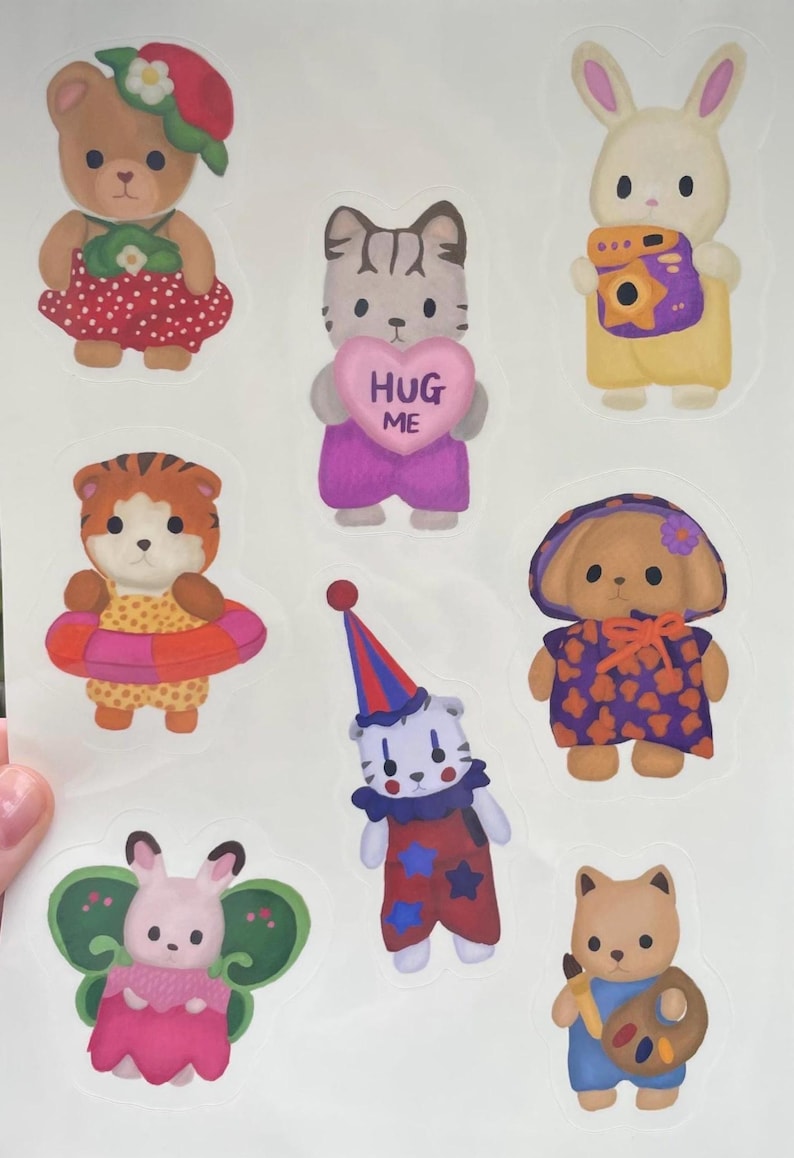 May include: A sheet of colorful stickers featuring various animal characters. The stickers include a bear, cat holding a heart that says "HUG ME", bunny with a camera, tiger with a float, clown, dog, and a bunny with butterfly wings.