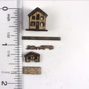 May include: Miniature wooden structures including a house, a train, a barn, and a brick wall. The house has windows and a door. The train has an engine and a car. The barn has an arched opening. The brick wall is rectangular.