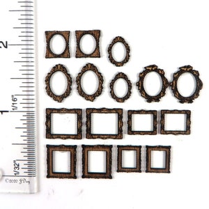 May include: A selection of miniature wooden frames, featuring oval and rectangular designs, in a warm brown hue. These intricately carved frames are likely for crafts or dollhouses. A ruler is present, providing scale in inches and fractions of an inch.