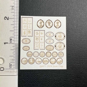 May include: A sheet of laser-cut paper with various designs, including oval frames, round plates, and rectangular panels with floral motifs. The sheet is labeled "LP075 2024 Jean Day".