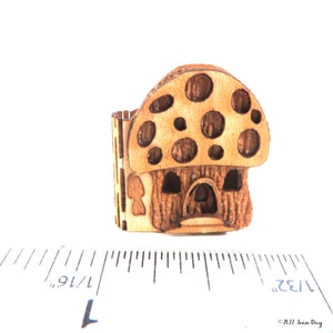 May include: A small wooden mushroom house with a brown and white finish. The mushroom has a domed top with white spots and a small door opening in the front.