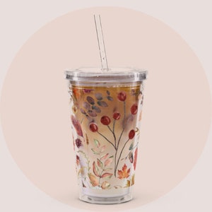 May include: Clear double-walled tumbler with a clear lid and straw. The tumbler is filled with a layered beverage. The exterior is decorated with a watercolour design of autumn leaves, berries, and foliage in shades of red, orange, and brown.