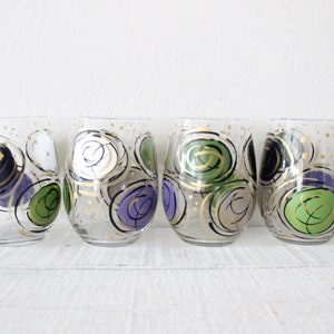 May include: Set of four clear glass wine glasses with hand-painted abstract designs in black, white, green, and purple.