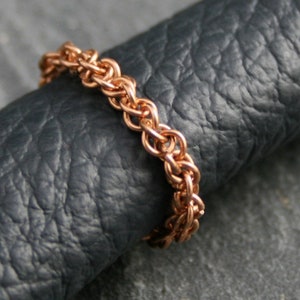 Könnte beinhalten: Ein Ring aus roségoldener Kette mit geflochtenem Design.