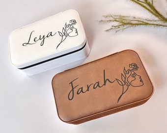 May include: Two personalized jewelry boxes, one white and one brown, with the names "Leya" and "Farah" engraved on them. Each box features a line drawing of a woman's face with a flower.